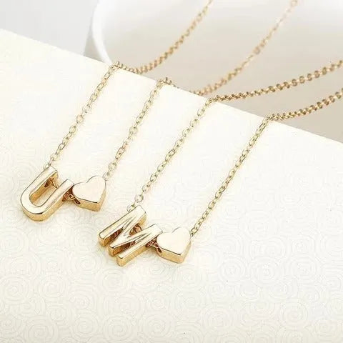 Gold alloy peach heart-shaped pendant featuring a single raised letter, shown from the front.