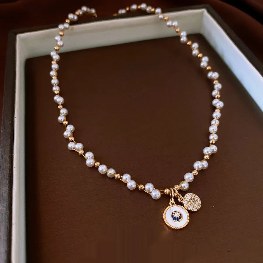 Gold electroplated necklace with round imitation pearl pendant and zircon detailing on adjustable clavicle chain