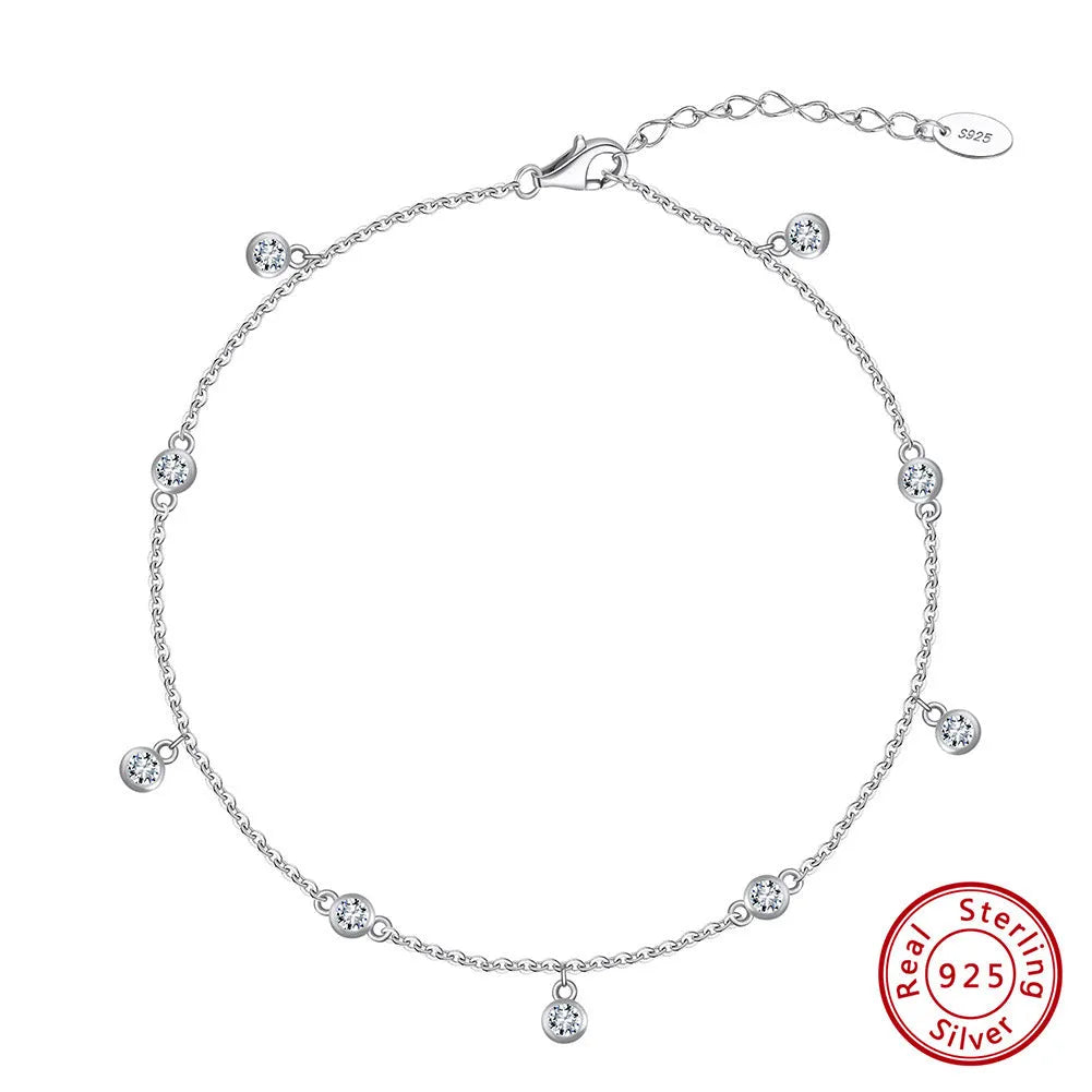 Close-up of a women's silver anklet with a geometric zirconium pendant on a simple chain.