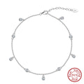 Close-up of a women's silver anklet with a geometric zirconium pendant on a simple chain.