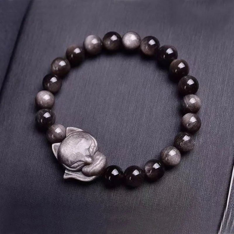 Close-up of black obsidian fox charm bracelet with 8mm polished bead on adjustable cord.
