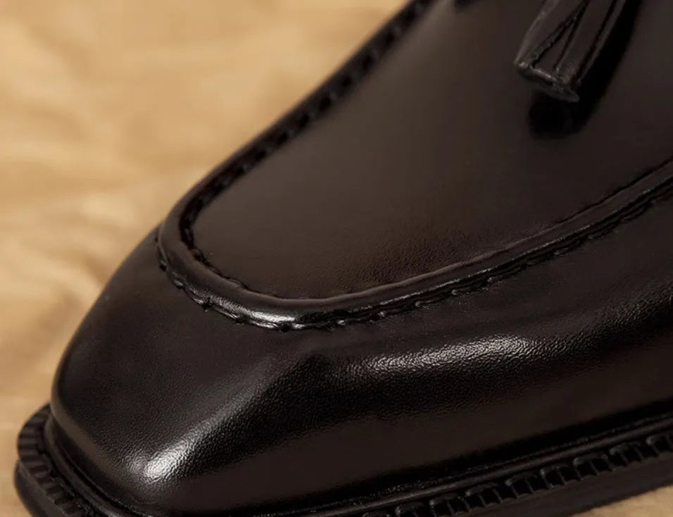 Men's black leather slip-on loafers with fringed detailing and polished finish