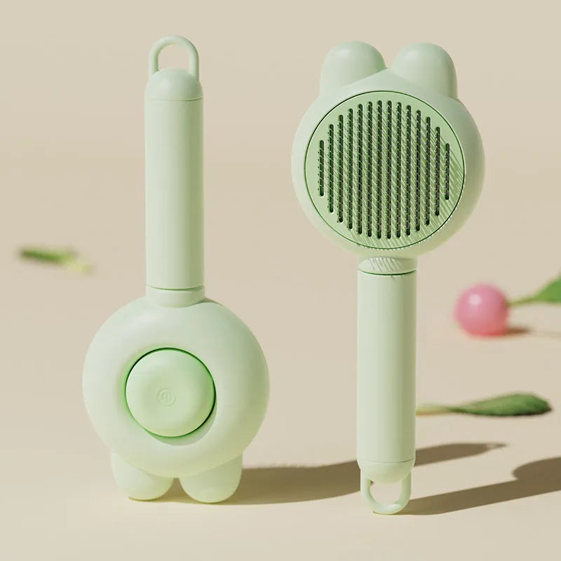 Green pet grooming brush with a self-cleaning button and a stainless steel comb.