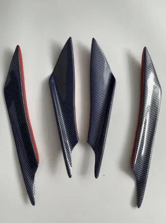 Set of four carbon fibre pattern bumper blade spoilers for car modification on a black background.