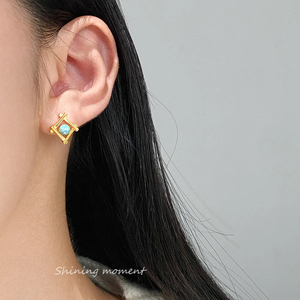 Geometric cross-shaped silver stud earrings with angular design, available in gold or silver finish.