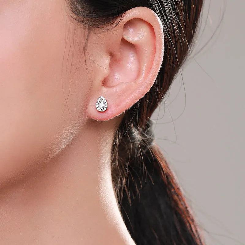 A pair of women's silver water drop shaped stud earrings on a plain background