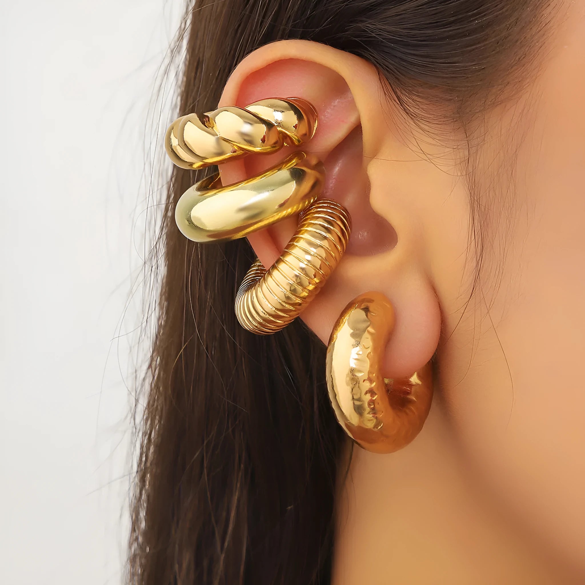 Set of four geometric clip-on earrings for women in gold and silver colours on a plain background