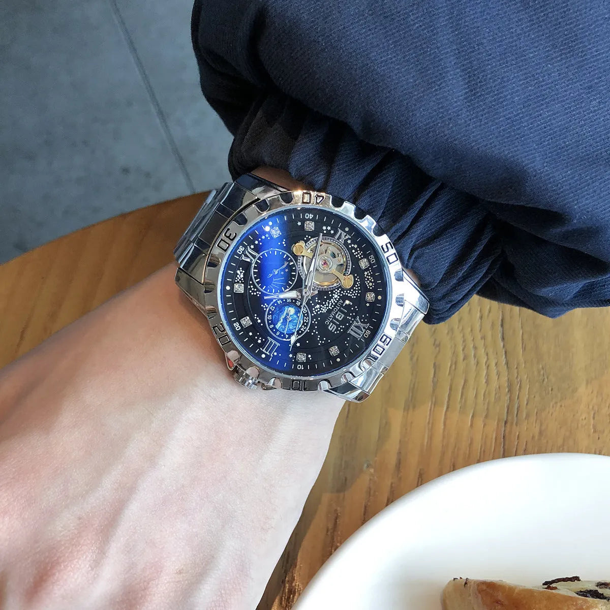 Men's silver case automatic watch with black starry dial, luminous hands, and brown leather strap