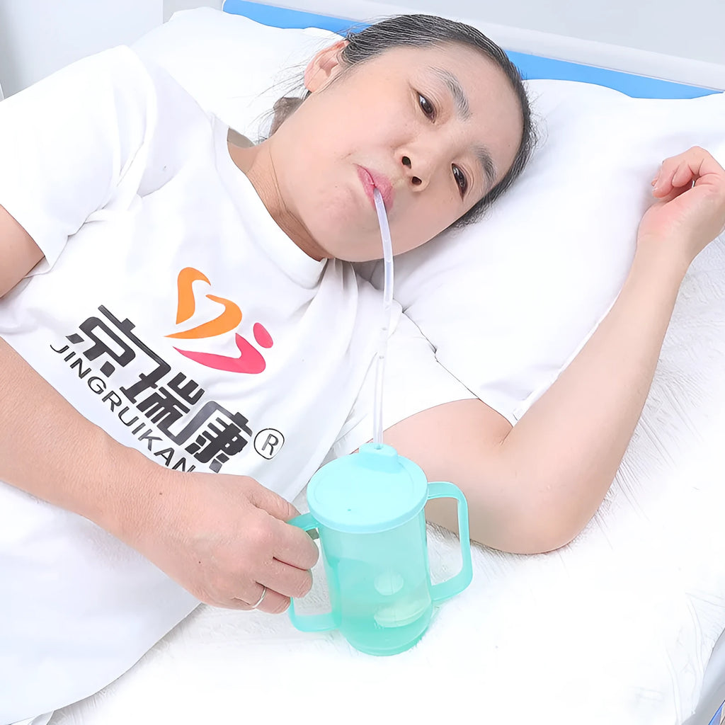 Oblique mouth choke-proof drinking cup for adults with handle and lid, shown with optional wrist splint.
