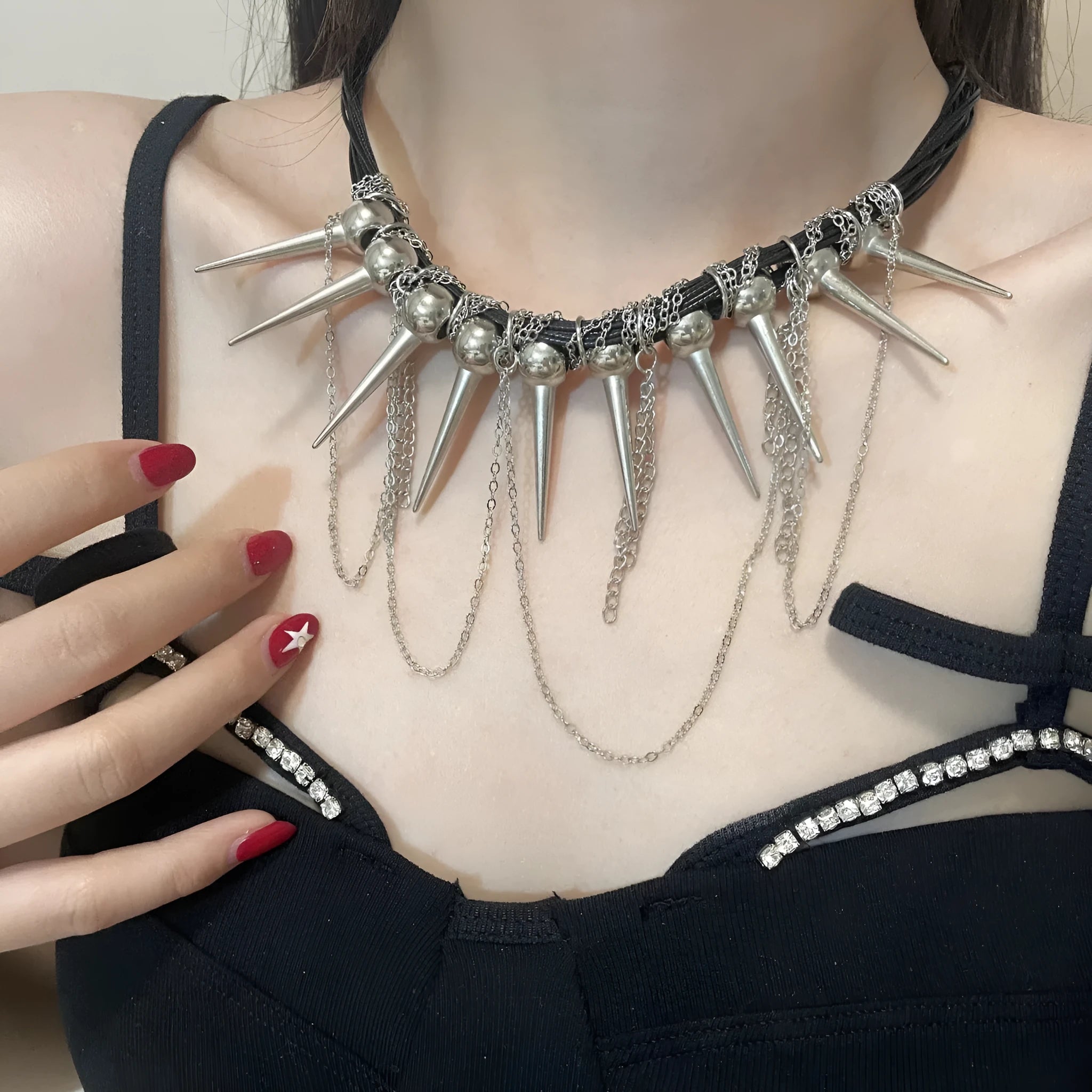 Leather necklace with winding round beads, rivet details, and a long tassel pendant in a metallic colour.