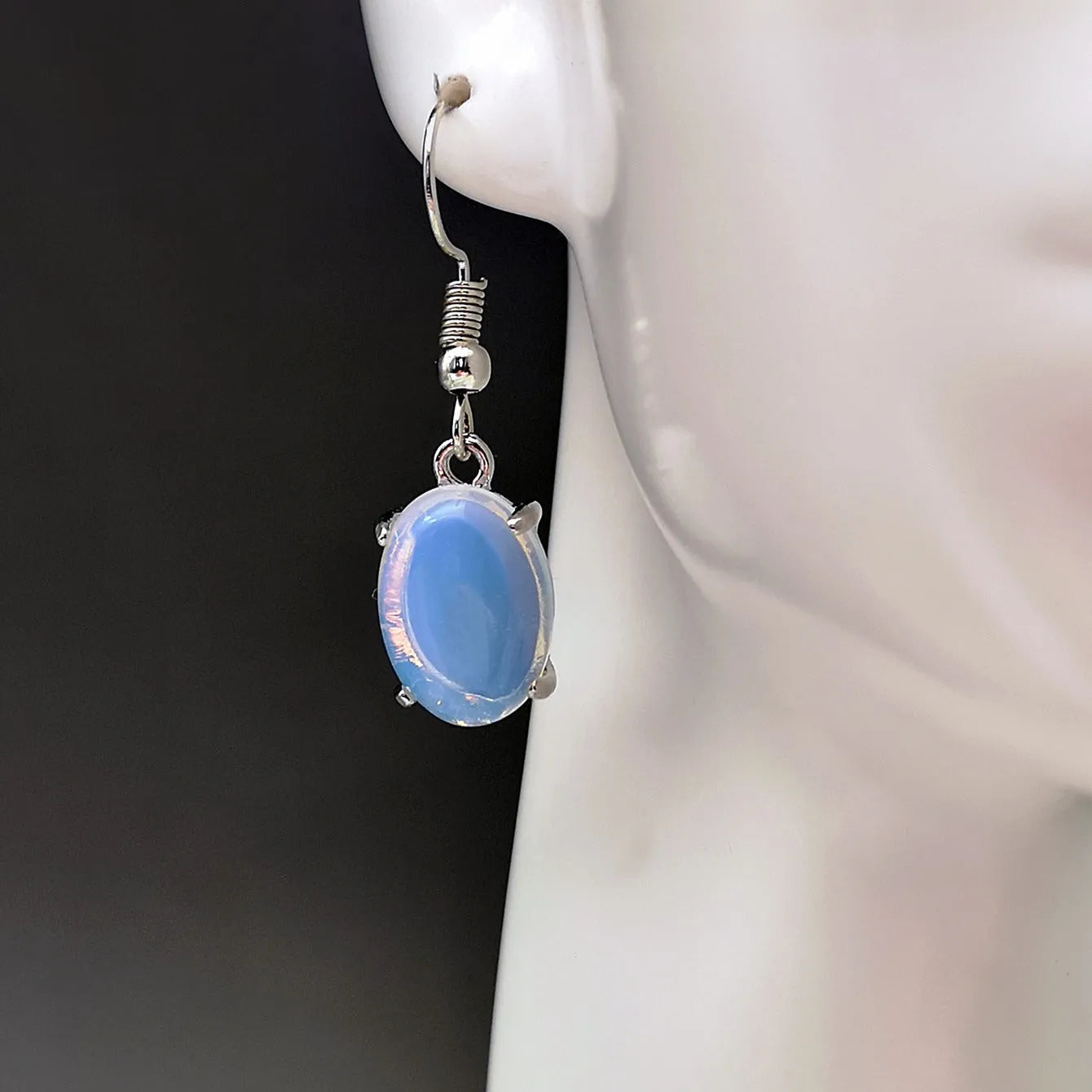 Moonlight white opal earrings with cross pendant and drop shape on retro moonstone style background