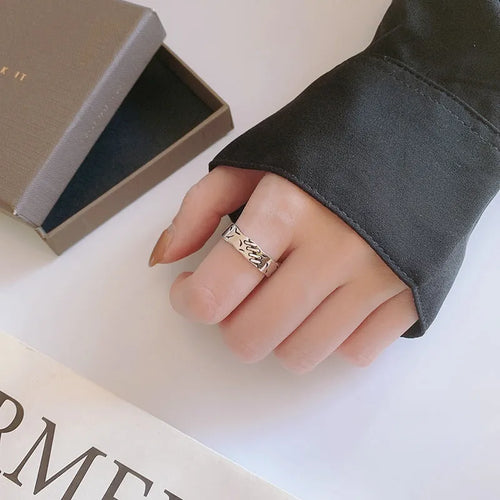 Black geometric copper ring with an adjustable opening on a white background.
