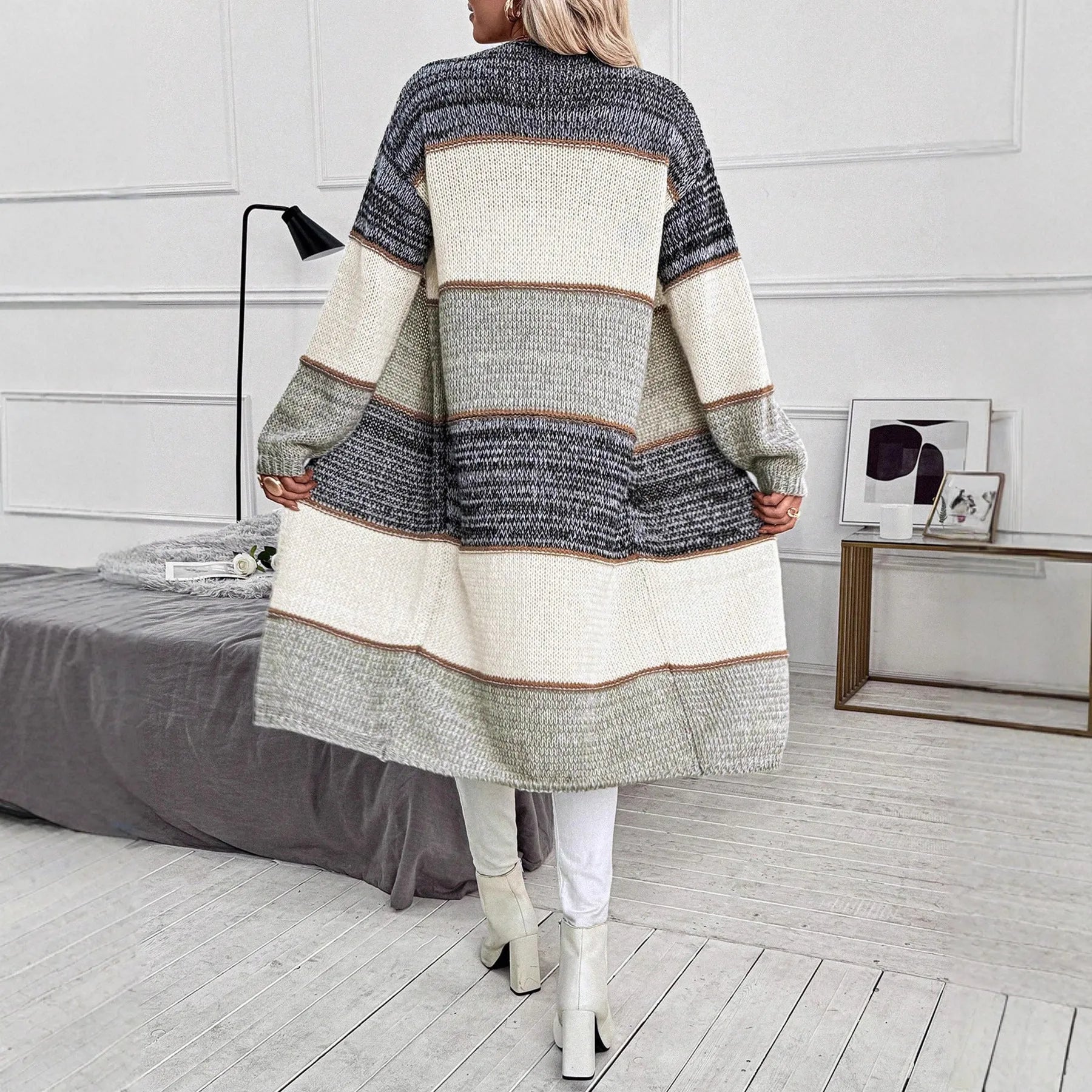 Grey women's loose-fit knitted long cardigan with long sleeves on a hanger.