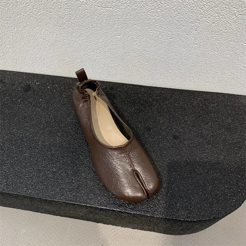 Women's black chunky heel pumps with a round toe and distinctive split toe horseshoe design detail.