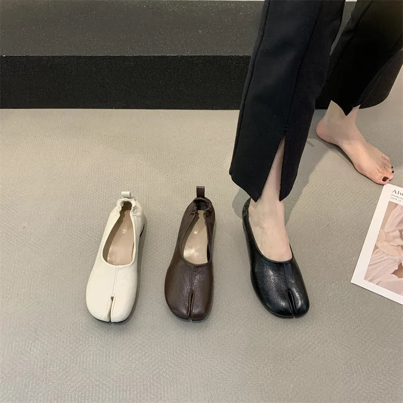 Women's black chunky heel pumps with a round toe and distinctive split toe horseshoe design detail.