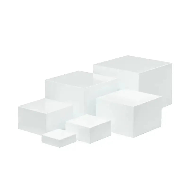 Six white plastic cube dessert display stands arranged on a table.