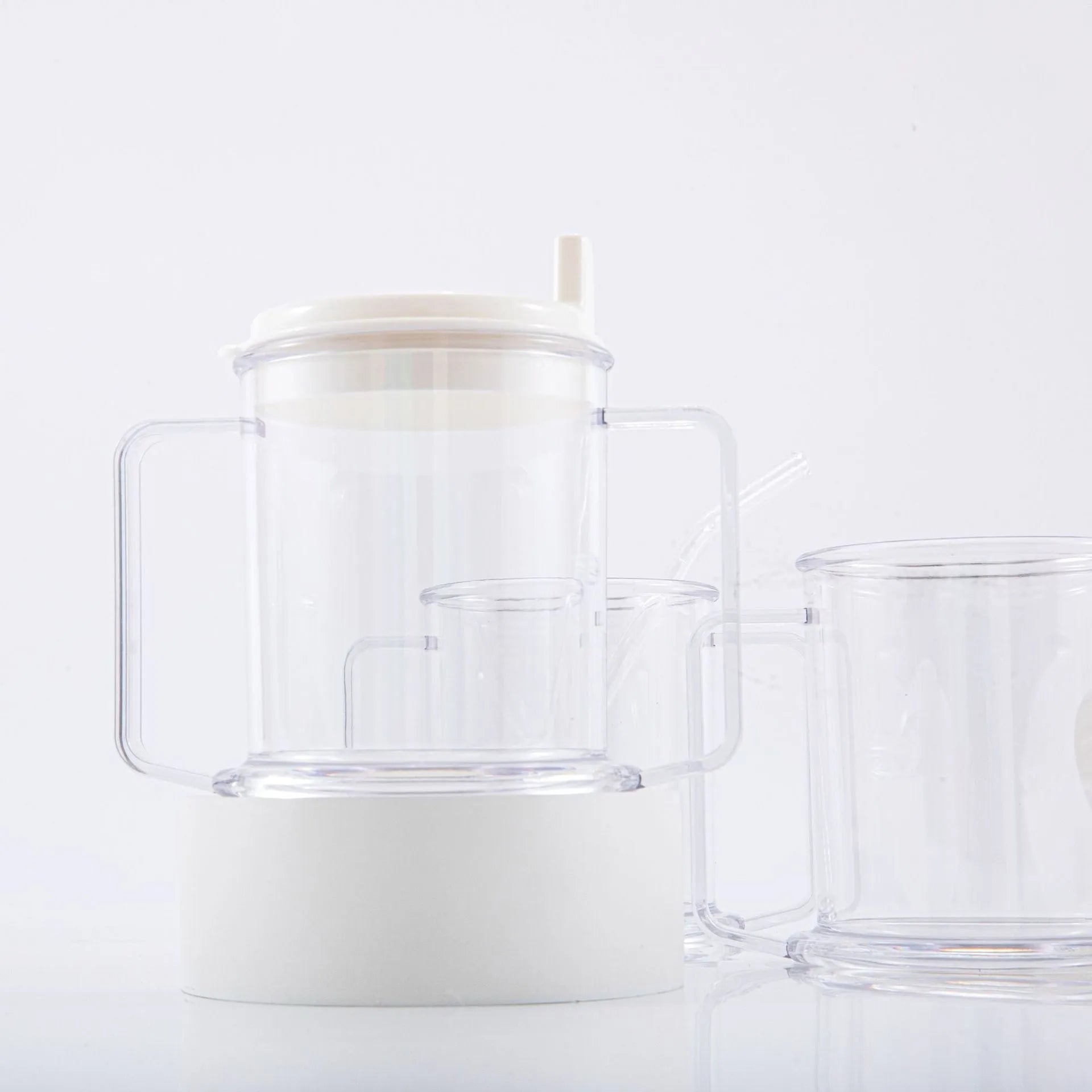 Transparent plastic drinking cup with a black spill-proof lid on a white background