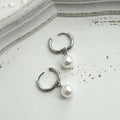 A pair of women's geometric alloy earrings with round pearl details and titanium steel posts.