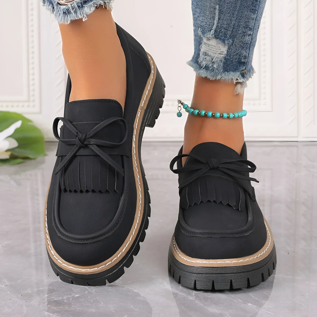 Women's plus size black loafers with tassel detail and a chunky flat rubber sole.