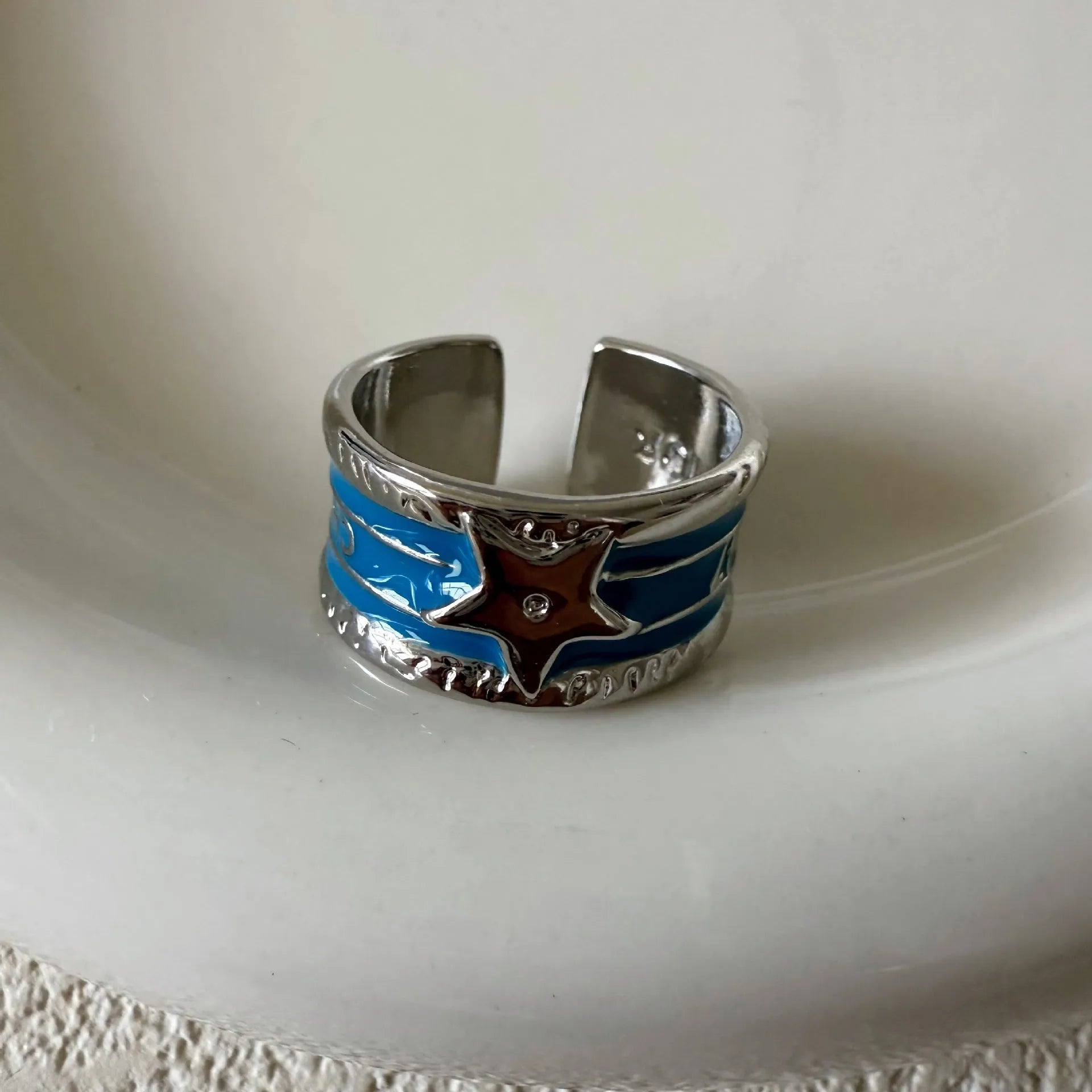 Adjustable copper geometric drop ring with distressed finish in black, red, blue, and black and red.