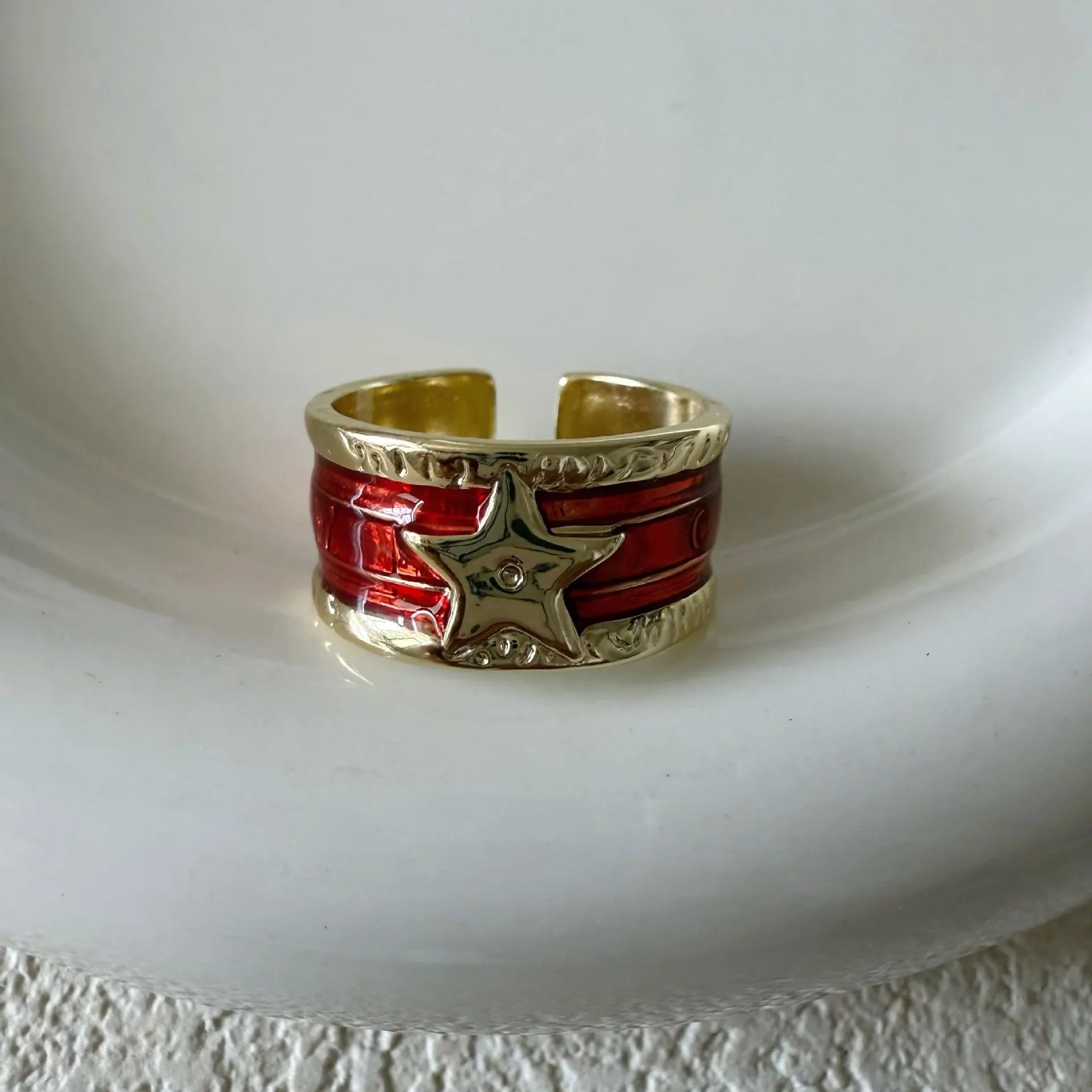 Adjustable copper geometric drop ring with distressed finish in black, red, blue, and black and red.