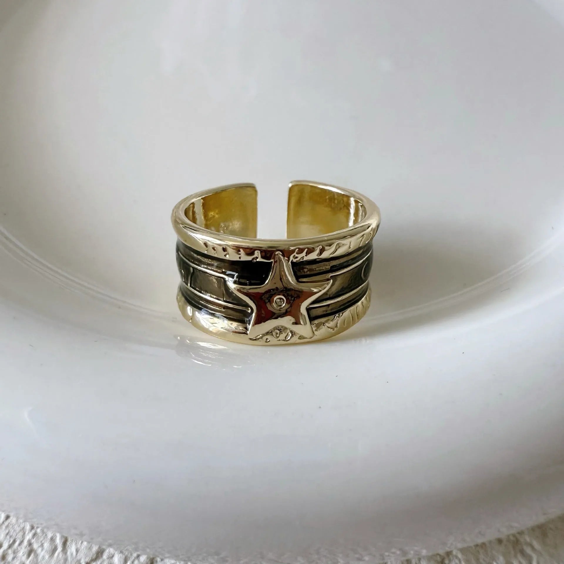 Adjustable copper geometric drop ring with distressed finish in black, red, blue, and black and red.
