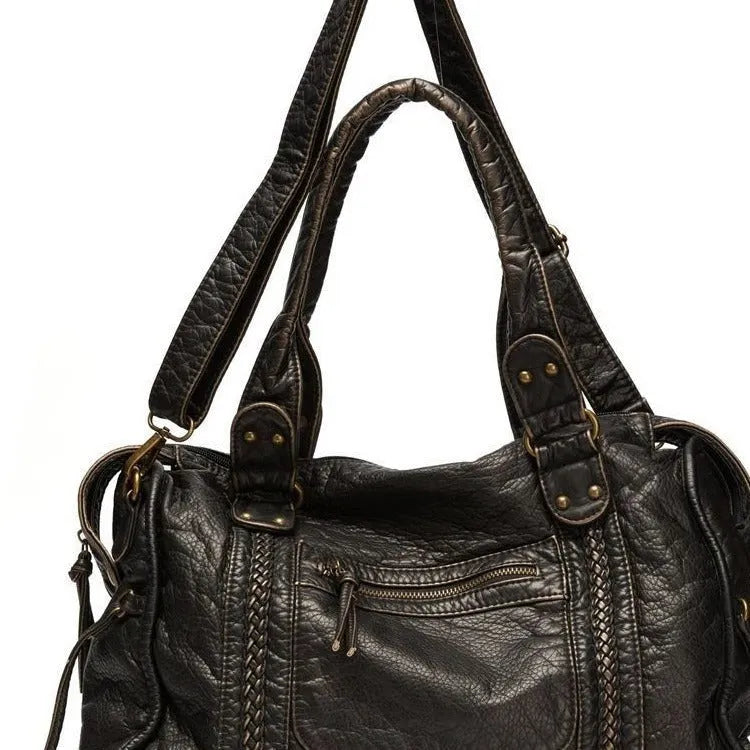 Women's retro motorcycle style messenger bag in bright black with golden edge, showing internal zipper compartments and single shoulder strap