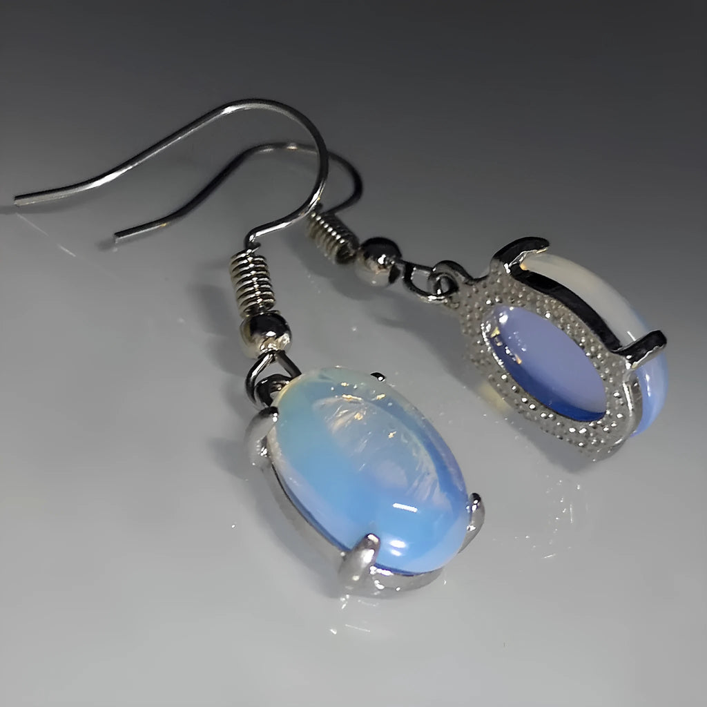 Moonlight white opal earrings with cross pendant and drop shape on retro moonstone style background