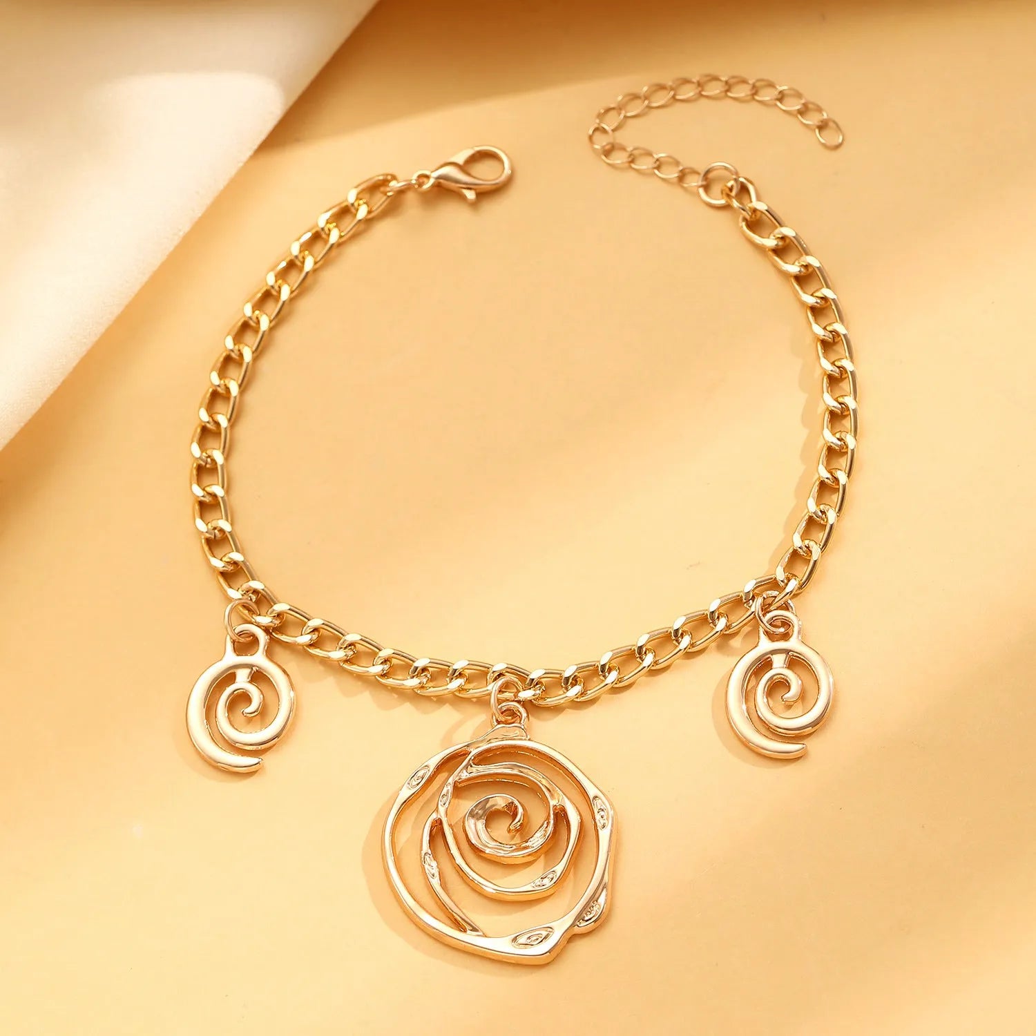 Spiral donut design women's jewellery set showing matching necklace, bracelet, and ear hooks in gold electroplated finish