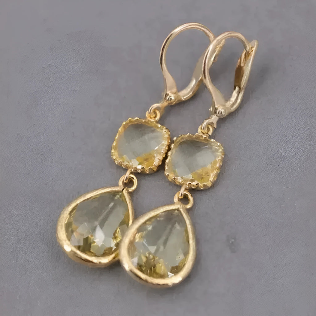 Gold geometric long fringe drop earrings with crystal and water droplet details on a white background.