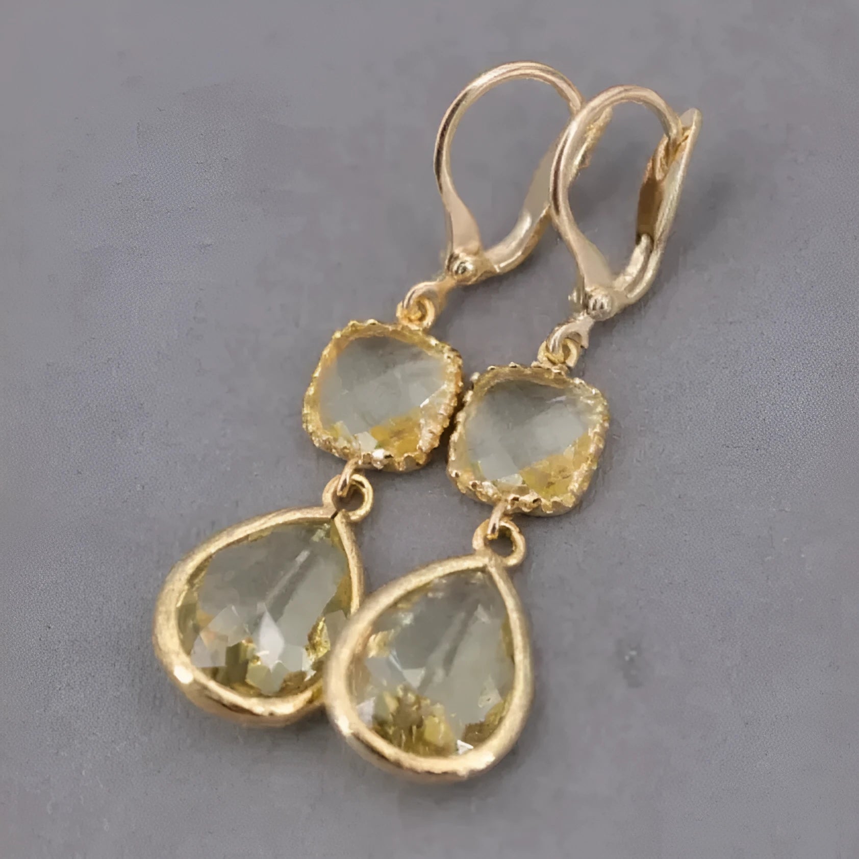 Gold geometric long fringe drop earrings with crystal and water droplet details on a white background.