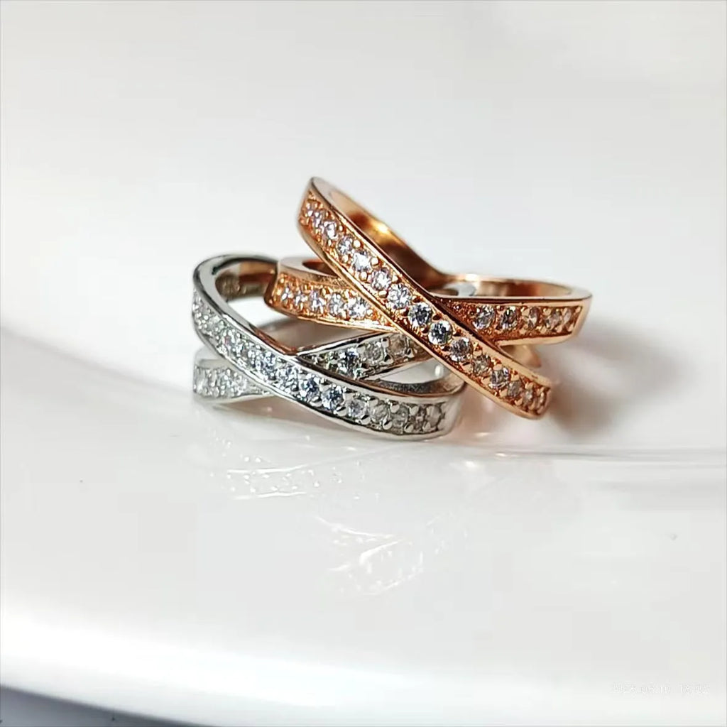 Close-up of a silver cross ring with micro-inlaid zircon details on a simple band.