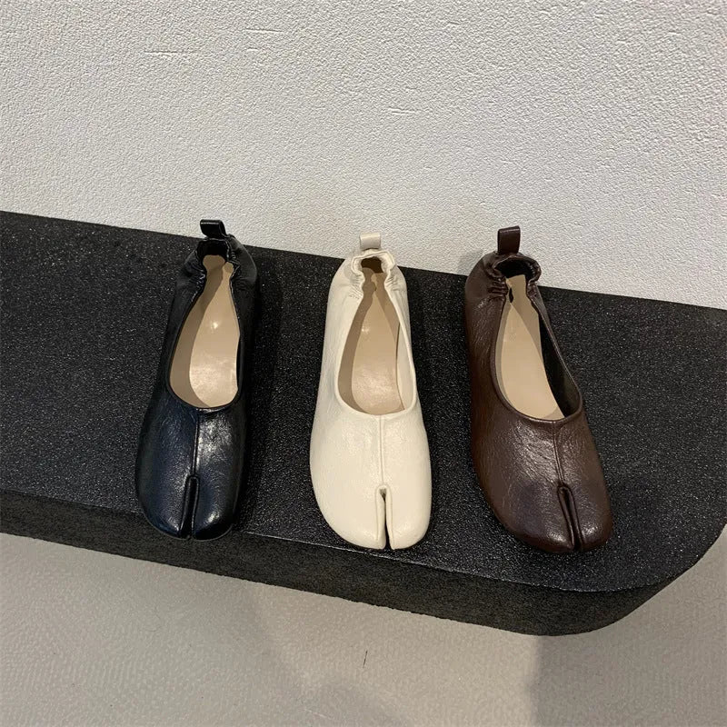 Women's black chunky heel pumps with a round toe and distinctive split toe horseshoe design detail.