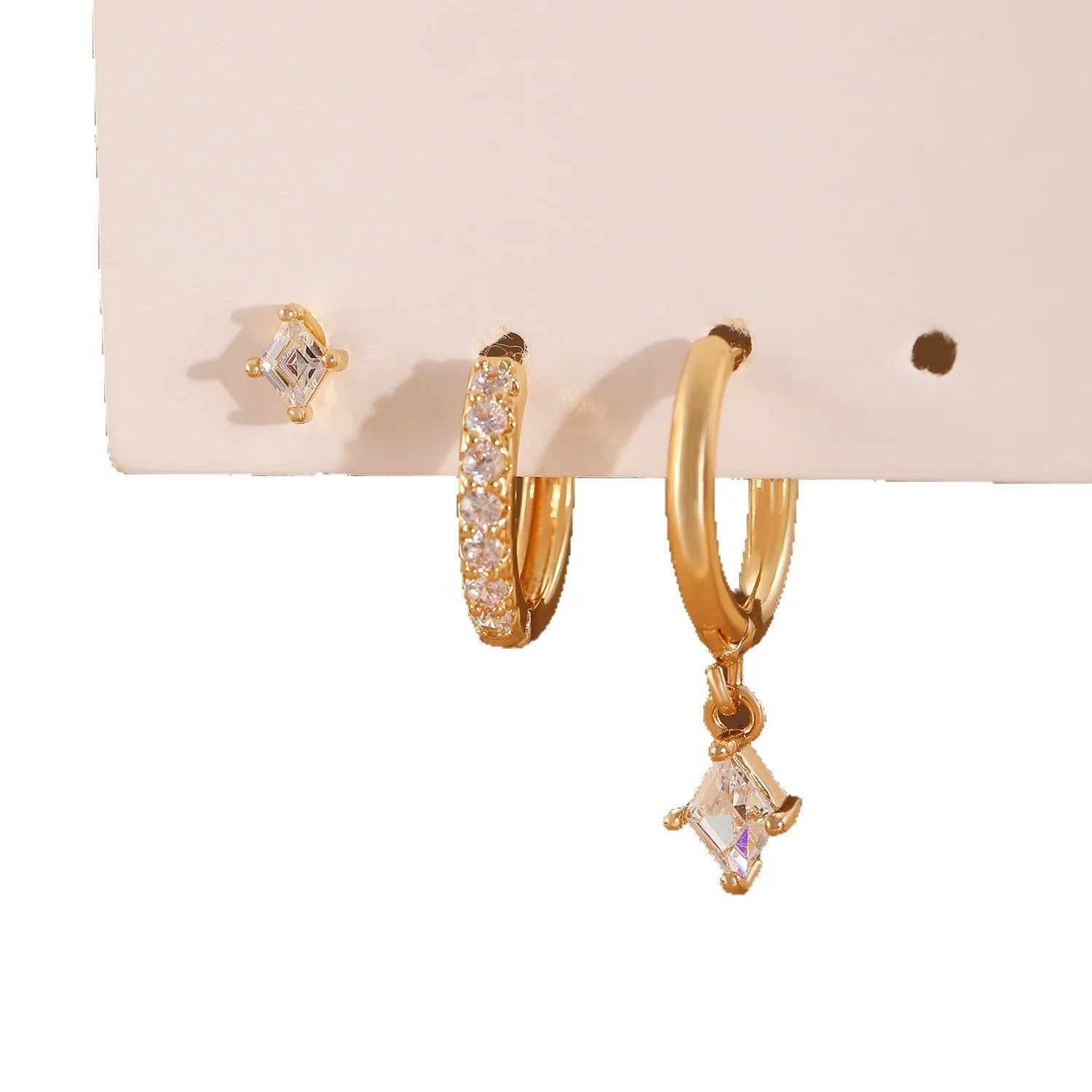 Ladies three-piece earring set with geometric zircon designs in gold and white colours showing pendant, stud, and clip styles