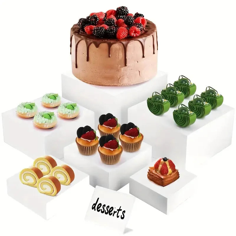 Six white plastic cube dessert display stands arranged on a table.