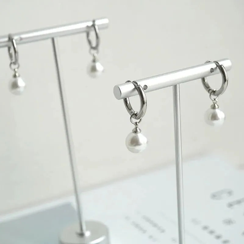A pair of women's geometric alloy earrings with round pearl details and titanium steel posts.