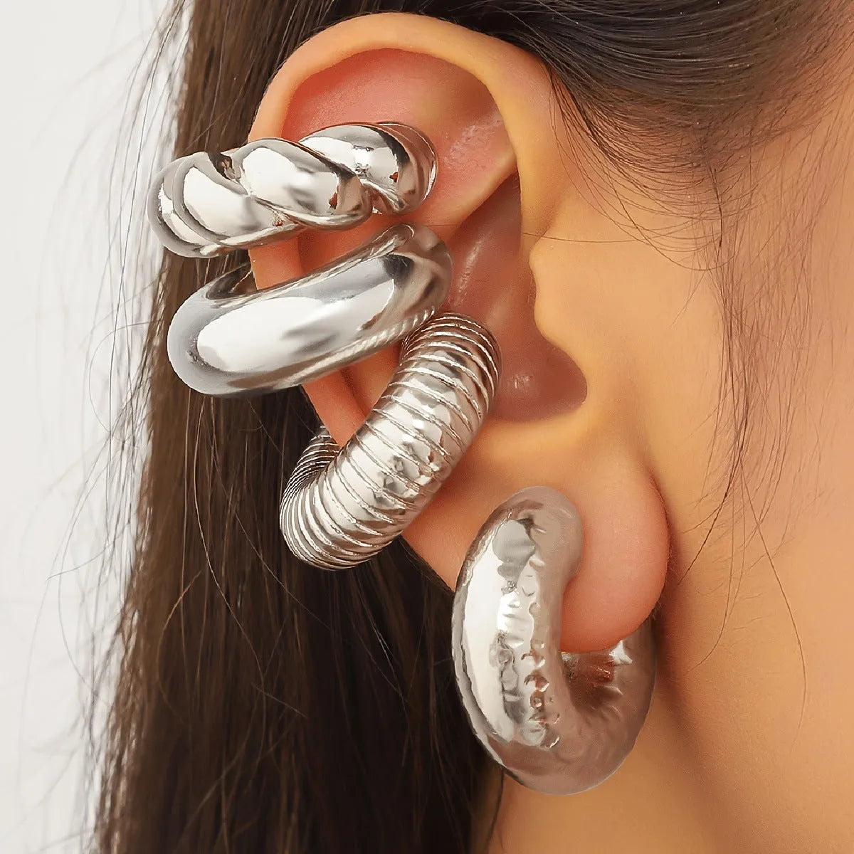 Set of four geometric clip-on earrings for women in gold and silver colours on a plain background