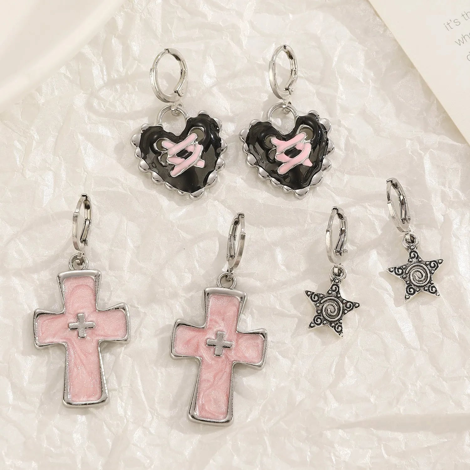 Women's alloy earrings showing cross, heart, and cat designs in white, black, and antique silver finishes.