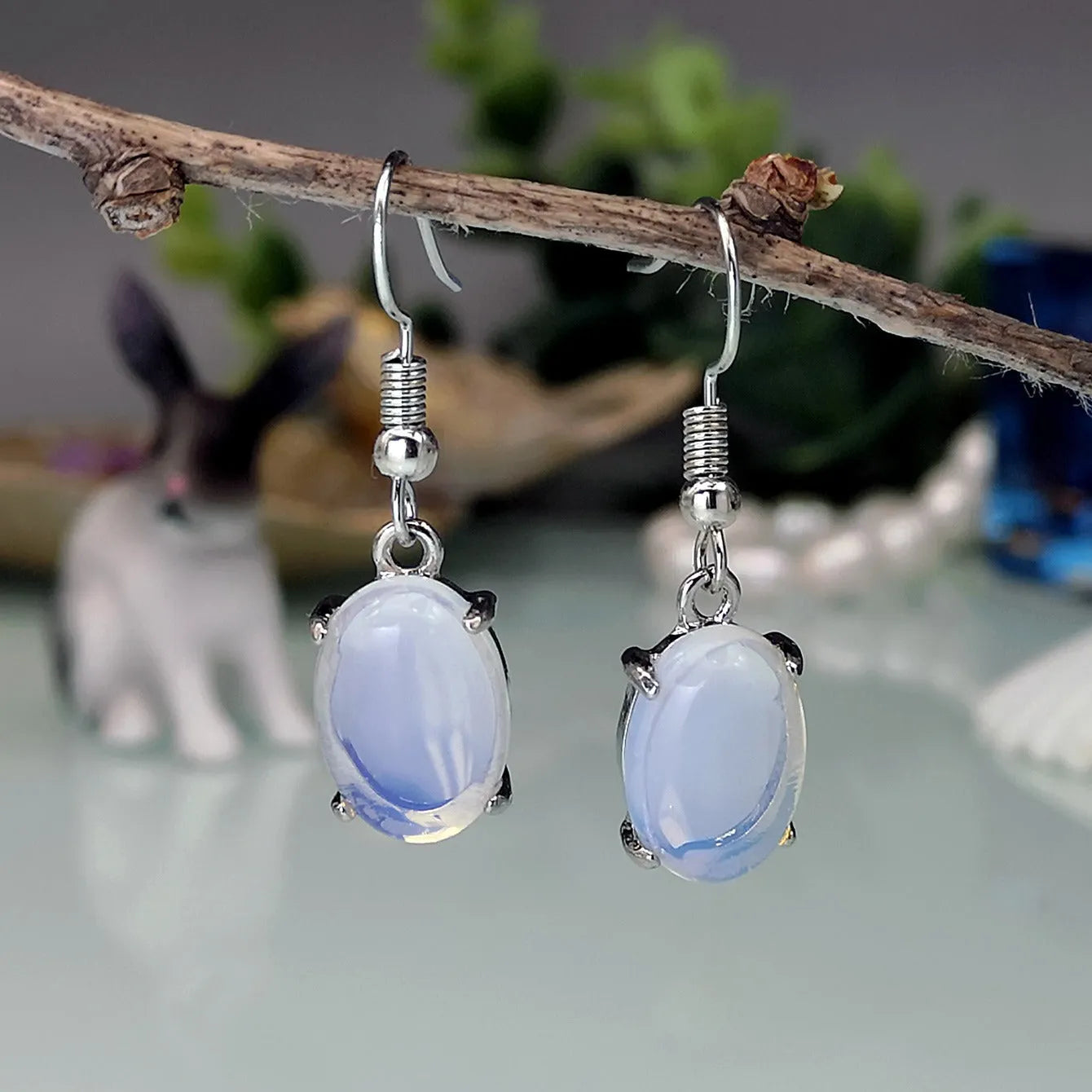 Moonlight white opal earrings with cross pendant and drop shape on retro moonstone style background