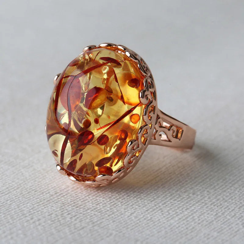 Close-up of a hand-carved beeswax amber ring in New Amber Type A colour on an alloy band, showing ethnic retro design.