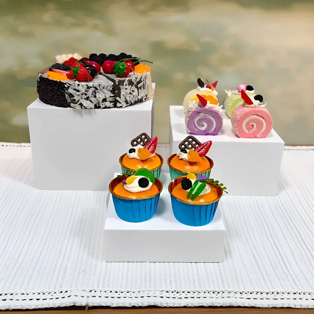 Six white plastic cube dessert display stands arranged on a table.