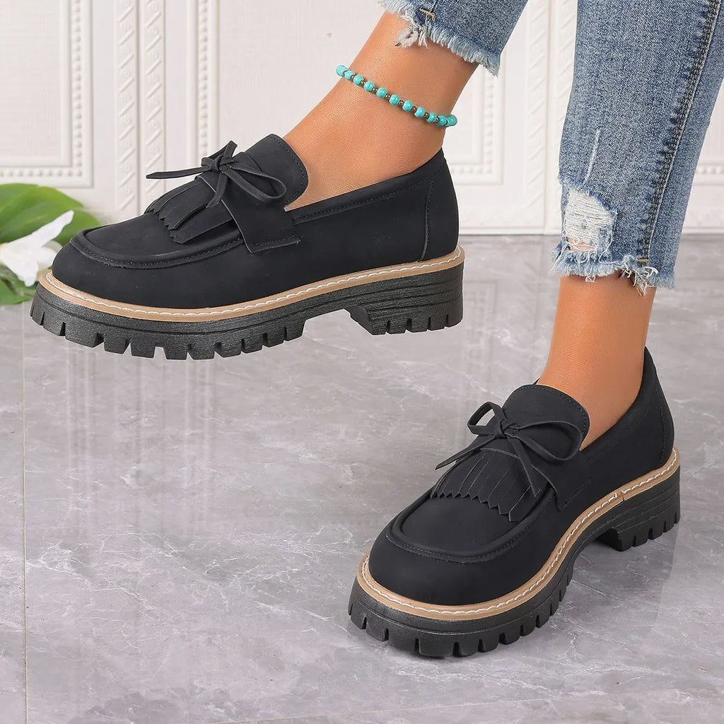 Women's plus size black loafers with tassel detail and a chunky flat rubber sole.