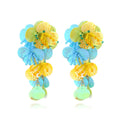 Close-up of handmade purple and green bead flower earrings with leaf details on a white background.