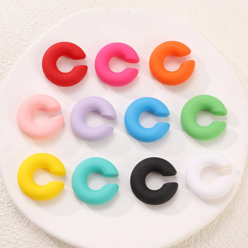 A pair of matte coarse finish round C-shaped clip-on earrings for women, shown in a candy colour.