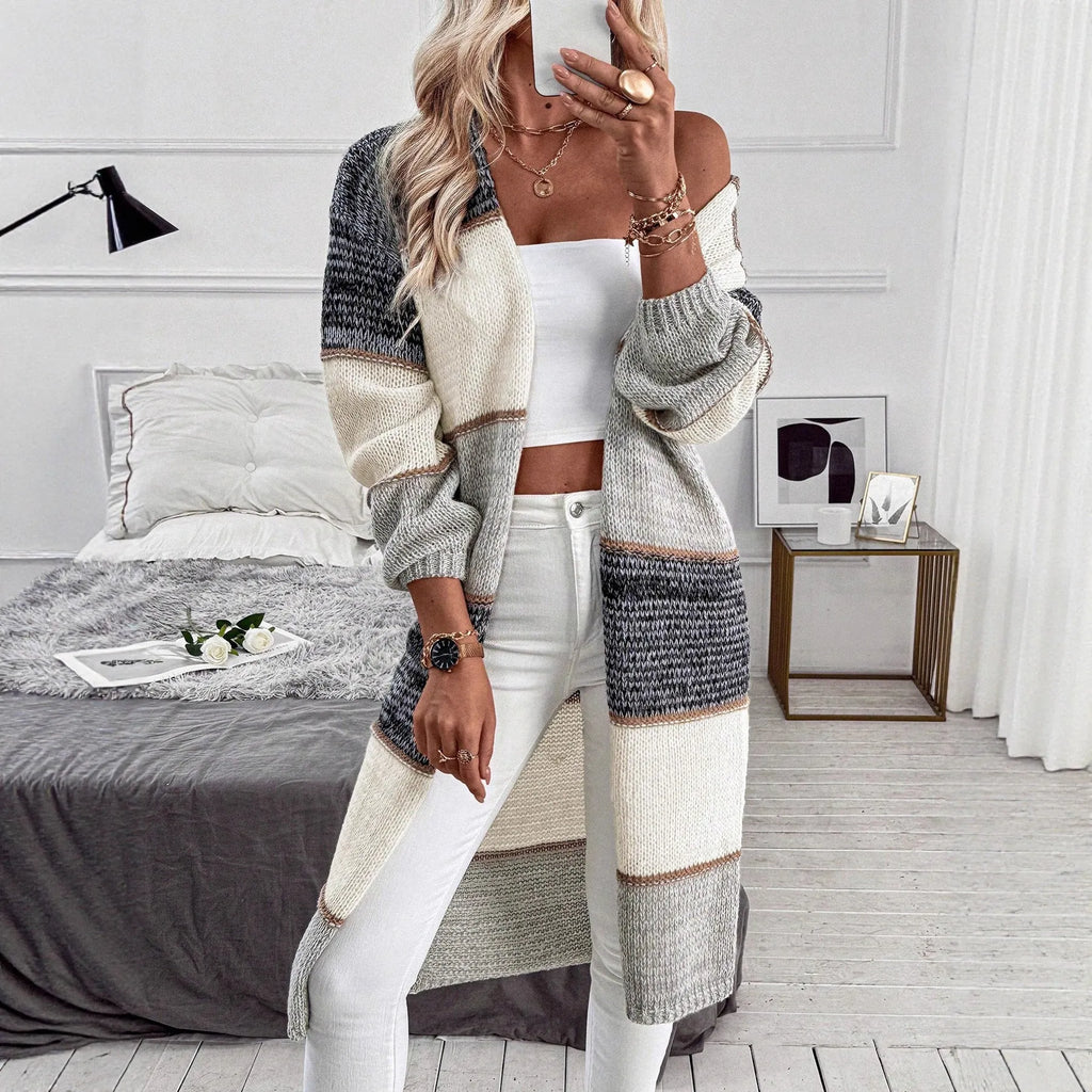 Grey women's loose-fit knitted long cardigan with long sleeves on a hanger.