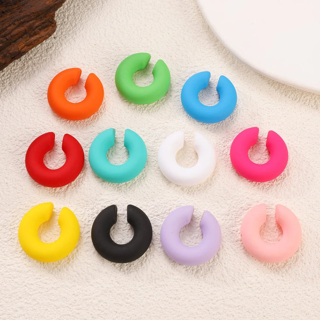 A pair of matte coarse finish round C-shaped clip-on earrings for women, shown in a candy colour.