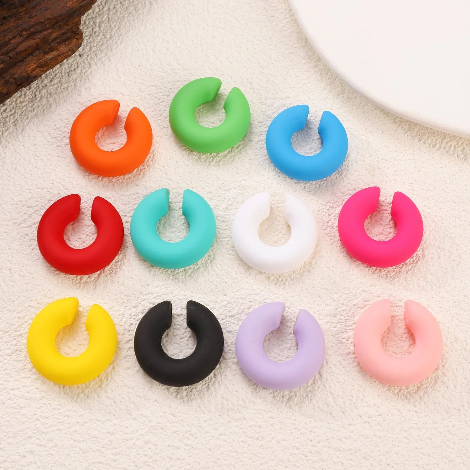 A pair of matte coarse finish round C-shaped clip-on earrings for women, shown in a candy colour.