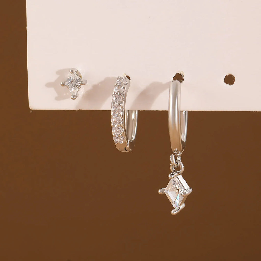 Ladies three-piece earring set with geometric zircon designs in gold and white colours showing pendant, stud, and clip styles
