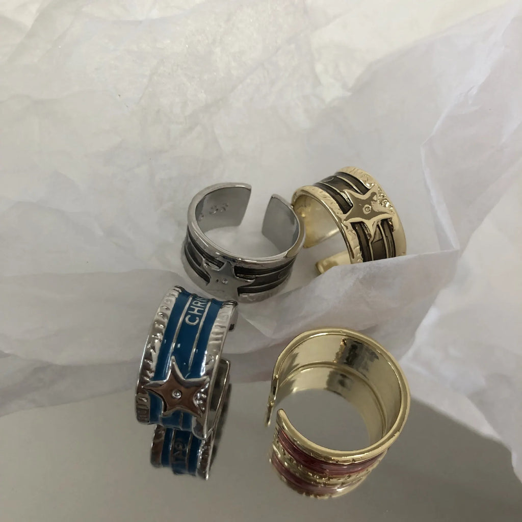 Adjustable copper geometric drop ring with distressed finish in black, red, blue, and black and red.