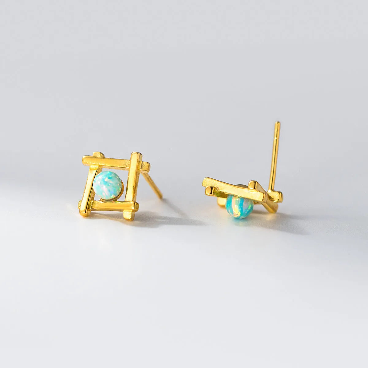 Geometric cross-shaped silver stud earrings with angular design, available in gold or silver finish.